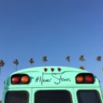 ciel bleu, palmier, bus vert sur lequel est écrit "Never stress"